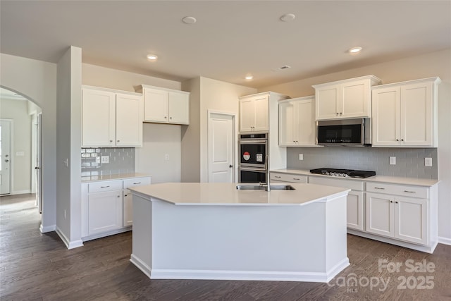 kitchen featuring stainless steel appliances, white cabinetry, sink, and a center island with sink