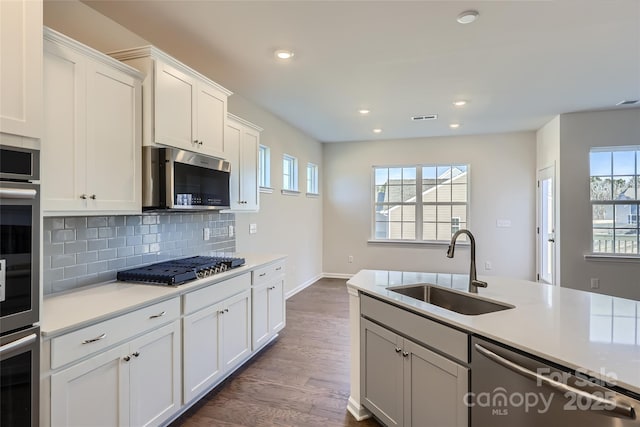 kitchen featuring sink, appliances with stainless steel finishes, dark hardwood / wood-style floors, decorative backsplash, and white cabinets