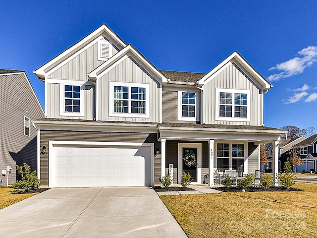 view of front of property featuring a porch, a front yard, and a garage