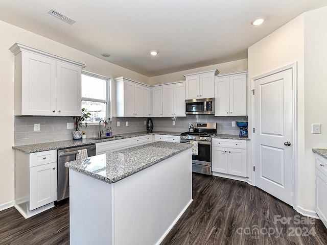 kitchen featuring appliances with stainless steel finishes, dark hardwood / wood-style flooring, white cabinetry, and a kitchen island