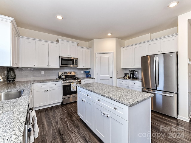 kitchen featuring white cabinets, sink, appliances with stainless steel finishes, dark hardwood / wood-style flooring, and light stone counters