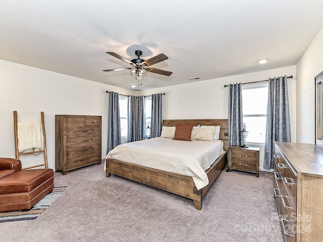 bedroom featuring light carpet, multiple windows, and ceiling fan