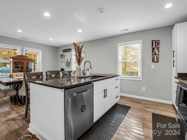 kitchen featuring sink, stainless steel dishwasher, light wood-type flooring, a kitchen bar, and white cabinetry