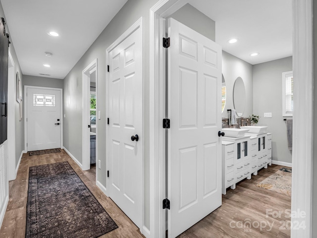 hallway featuring sink, plenty of natural light, and light wood-type flooring