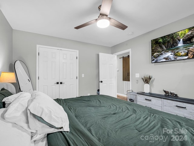 bedroom with ceiling fan, a barn door, and a closet