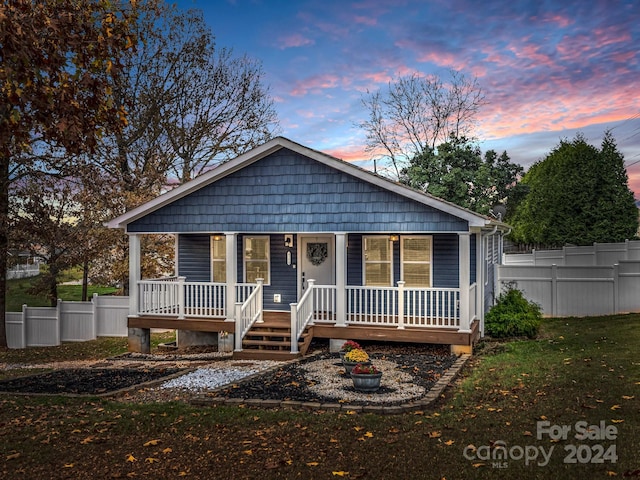 bungalow-style home with covered porch and a yard