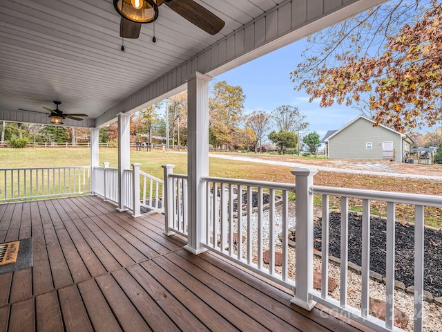 deck featuring ceiling fan, a yard, and a porch