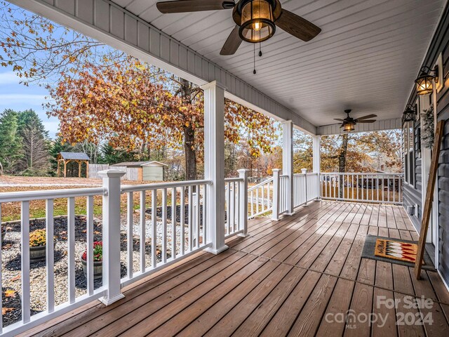 wooden deck with covered porch, a shed, and ceiling fan