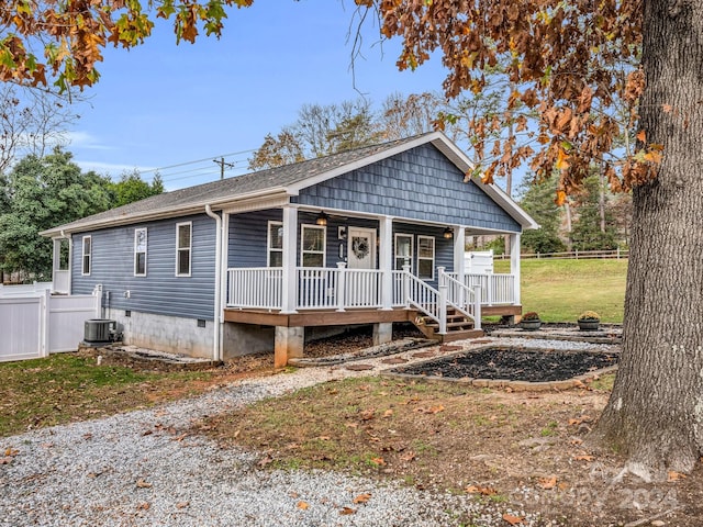 view of front of house with covered porch, central AC unit, and a front yard