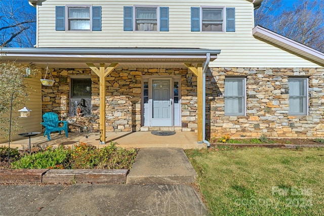 doorway to property featuring a lawn and a porch