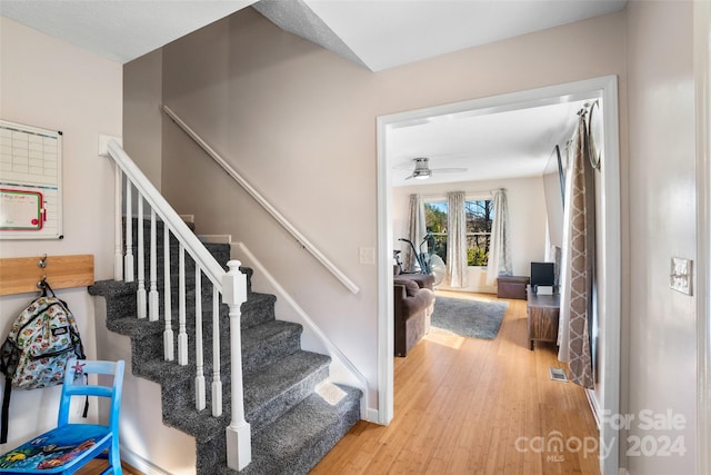 staircase with ceiling fan and hardwood / wood-style floors