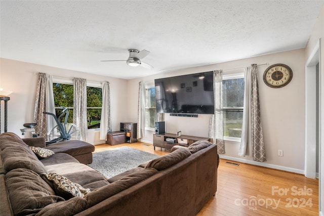 living room featuring a textured ceiling, light wood-type flooring, and ceiling fan