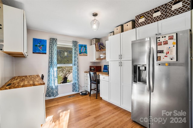 kitchen featuring wooden counters, stainless steel fridge, white cabinets, and pendant lighting