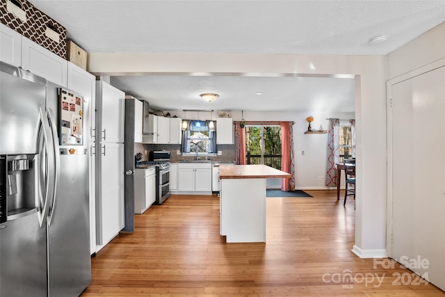 kitchen featuring sink, light wood-type flooring, appliances with stainless steel finishes, a kitchen island, and white cabinetry