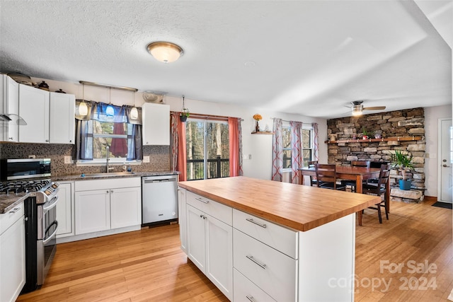 kitchen featuring white cabinets, appliances with stainless steel finishes, light hardwood / wood-style flooring, and wood counters