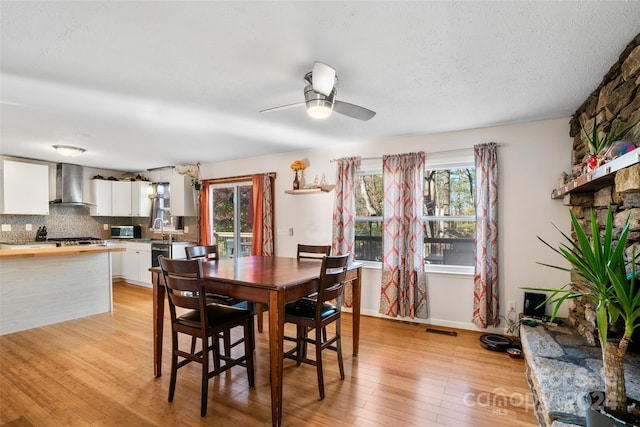 dining space with light hardwood / wood-style flooring, ceiling fan, and sink