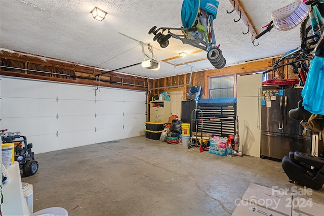 garage featuring stainless steel refrigerator and a garage door opener