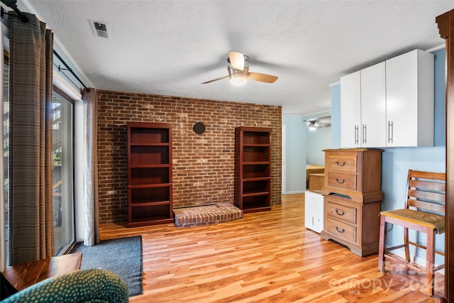 office area with ceiling fan, light wood-type flooring, and a textured ceiling