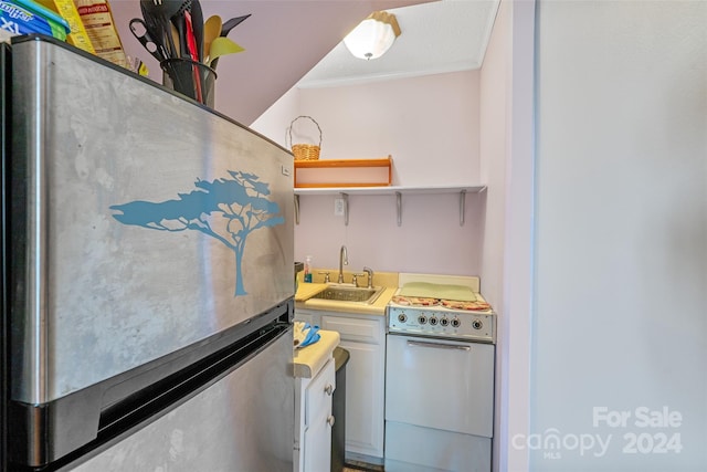 kitchen featuring stainless steel fridge, sink, ornamental molding, and range