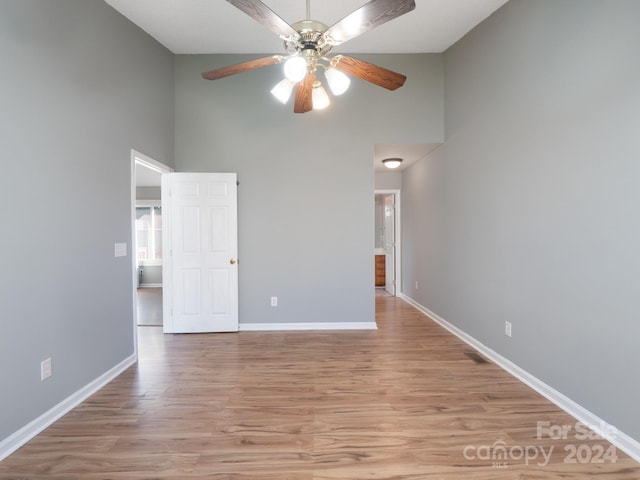 unfurnished room with a high ceiling, light hardwood / wood-style floors, and ceiling fan