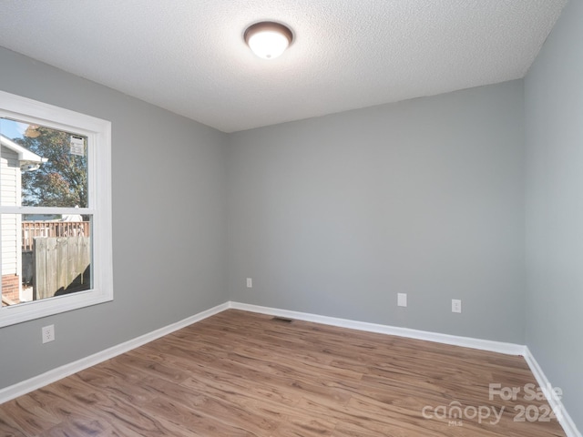 empty room featuring a textured ceiling and light hardwood / wood-style floors