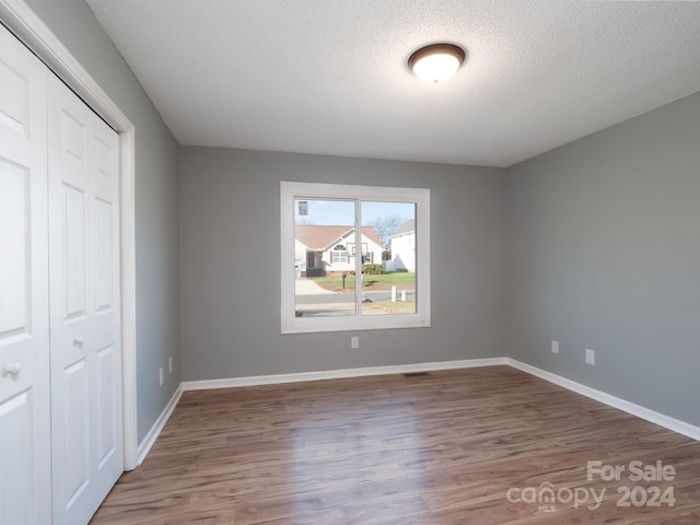 unfurnished bedroom featuring a textured ceiling, hardwood / wood-style flooring, and a closet