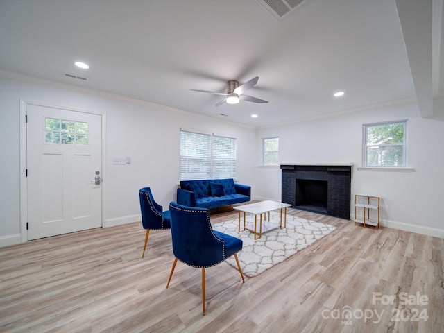 living room featuring a brick fireplace, light hardwood / wood-style flooring, and a healthy amount of sunlight