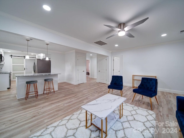 sitting room featuring a barn door, light hardwood / wood-style flooring, ceiling fan, and crown molding