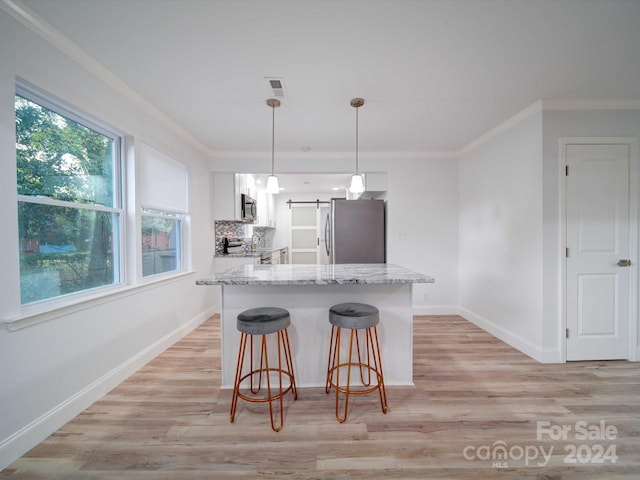 kitchen featuring white cabinetry, a barn door, light stone counters, pendant lighting, and appliances with stainless steel finishes