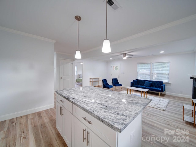 kitchen with light stone counters, ornamental molding, decorative light fixtures, light hardwood / wood-style flooring, and white cabinetry