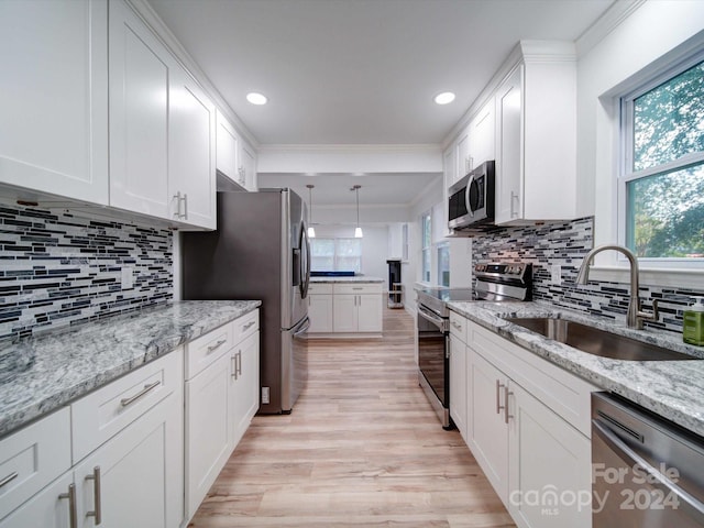 kitchen with backsplash, sink, light hardwood / wood-style flooring, white cabinetry, and stainless steel appliances