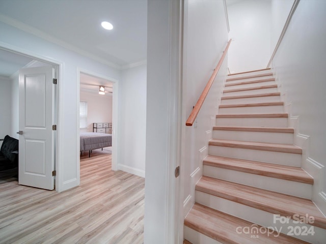 stairs with wood-type flooring and ornamental molding