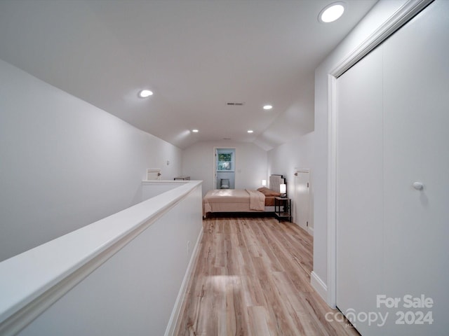 corridor with light hardwood / wood-style floors and vaulted ceiling