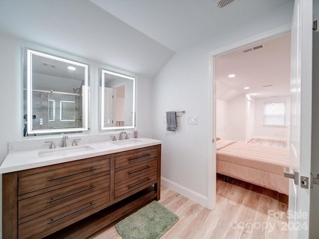 bathroom featuring vanity, wood-type flooring, a shower with door, and vaulted ceiling