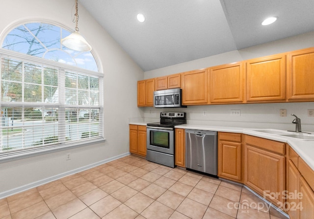 kitchen with stainless steel appliances, vaulted ceiling, sink, light tile patterned floors, and hanging light fixtures