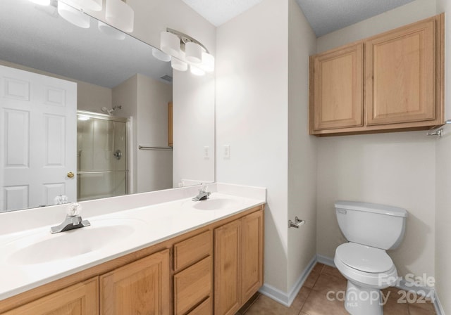 bathroom with vanity, tile patterned floors, toilet, a textured ceiling, and a shower with shower door