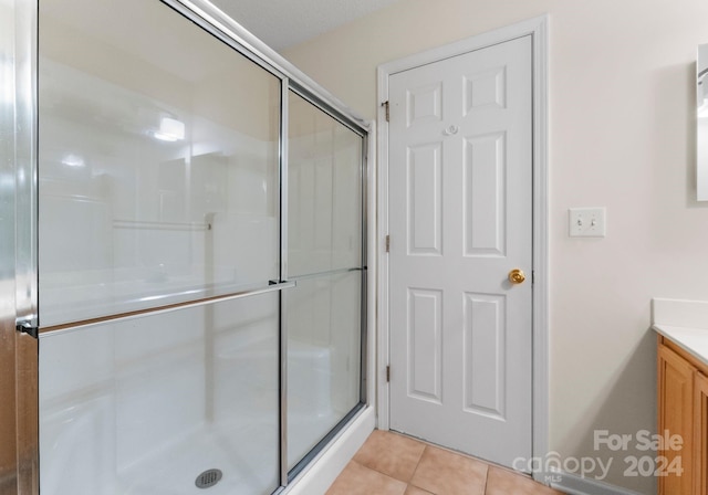 bathroom with tile patterned flooring, vanity, and an enclosed shower