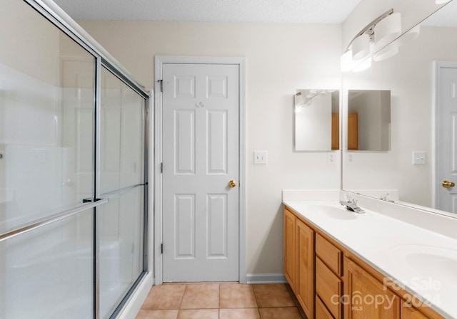 bathroom featuring tile patterned flooring, vanity, an enclosed shower, and a textured ceiling