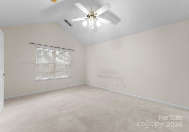 carpeted spare room featuring ceiling fan and vaulted ceiling