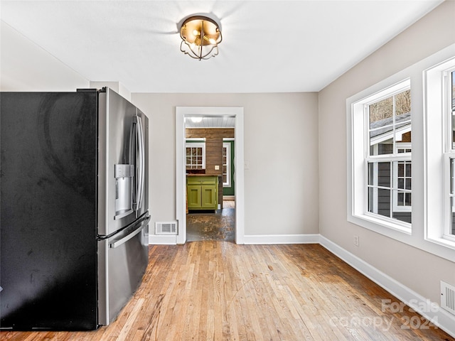 kitchen featuring stainless steel fridge, green cabinets, and light hardwood / wood-style flooring