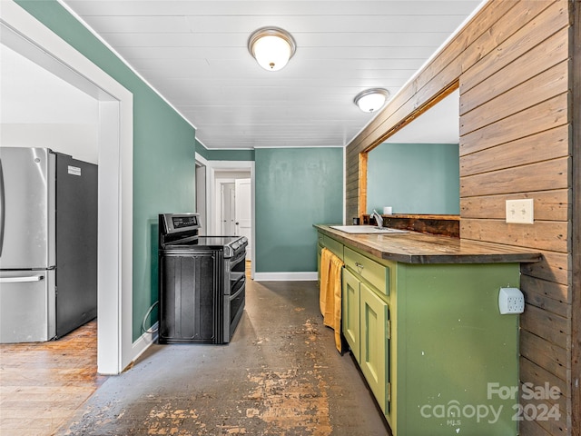 kitchen with stainless steel fridge, wooden walls, sink, green cabinetry, and range with electric stovetop