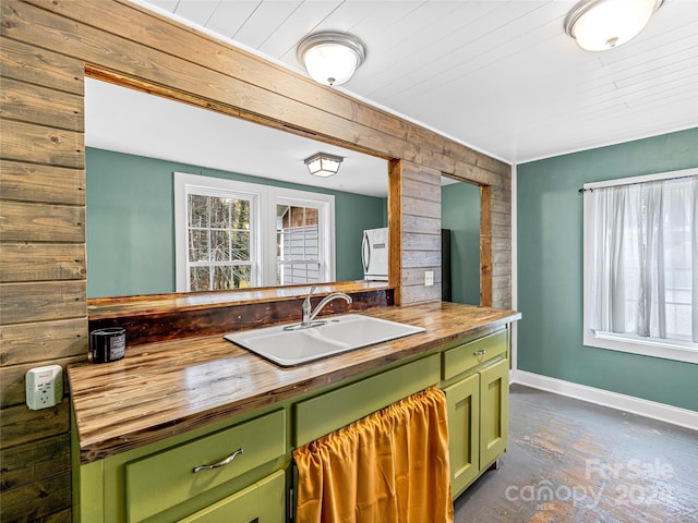 kitchen featuring wood walls, wooden counters, green cabinets, sink, and wood ceiling