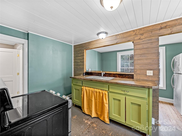 kitchen featuring butcher block countertops, wood walls, electric stove, and sink