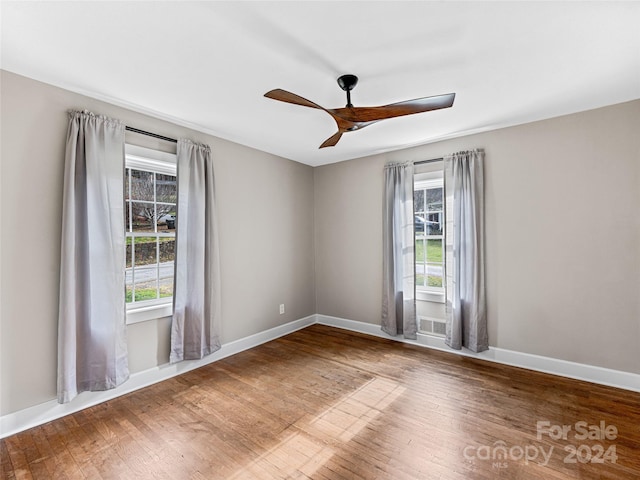 empty room with ceiling fan, a healthy amount of sunlight, and hardwood / wood-style flooring