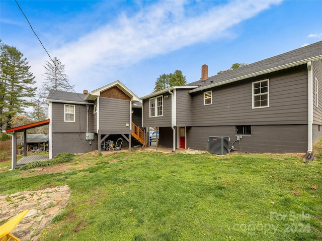 rear view of property with cooling unit and a lawn