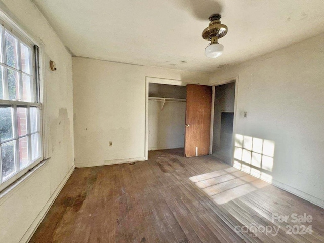 unfurnished bedroom with a closet and dark wood-type flooring