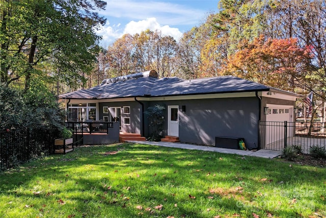 rear view of house featuring a garage, a yard, and a wooden deck