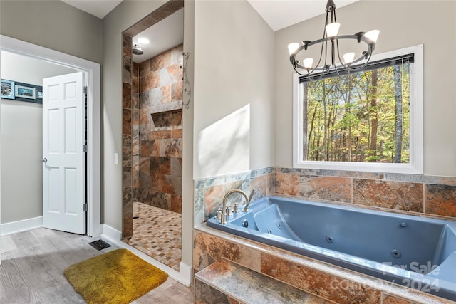 bathroom featuring wood-type flooring, an inviting chandelier, and separate shower and tub