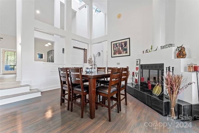 dining space with a towering ceiling, dark hardwood / wood-style floors, and a barn door