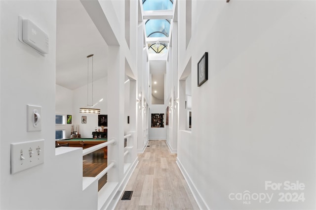 corridor featuring light wood-type flooring and a high ceiling